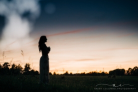 silhouette of a woman in a yoga pose in a field at sunset